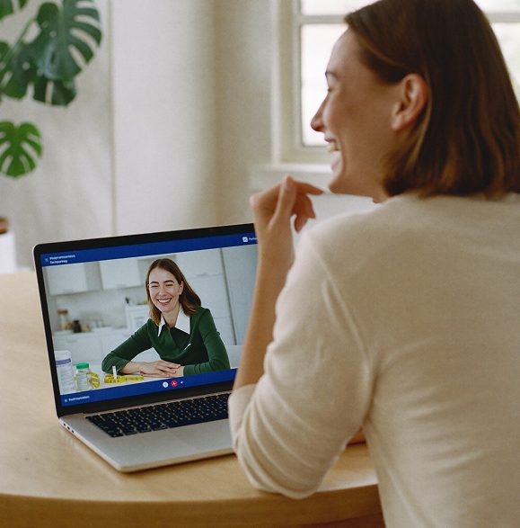 A woman smiling during an online video consultation with a pharmacist